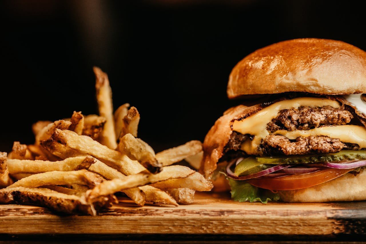 About Mouthwatering cheeseburger and crispy fries on a wooden board, perfectly capturing fast food appeal.
